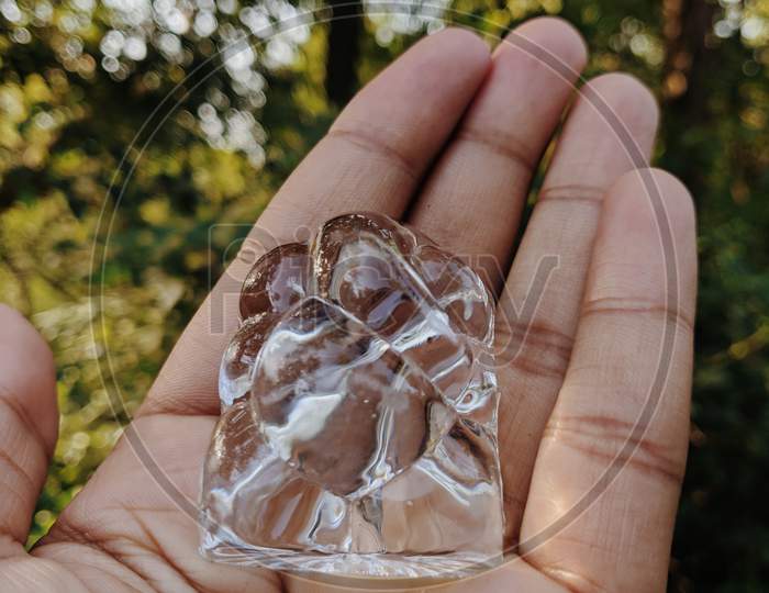 Hand holding a glass figurine of lord Ganesha.