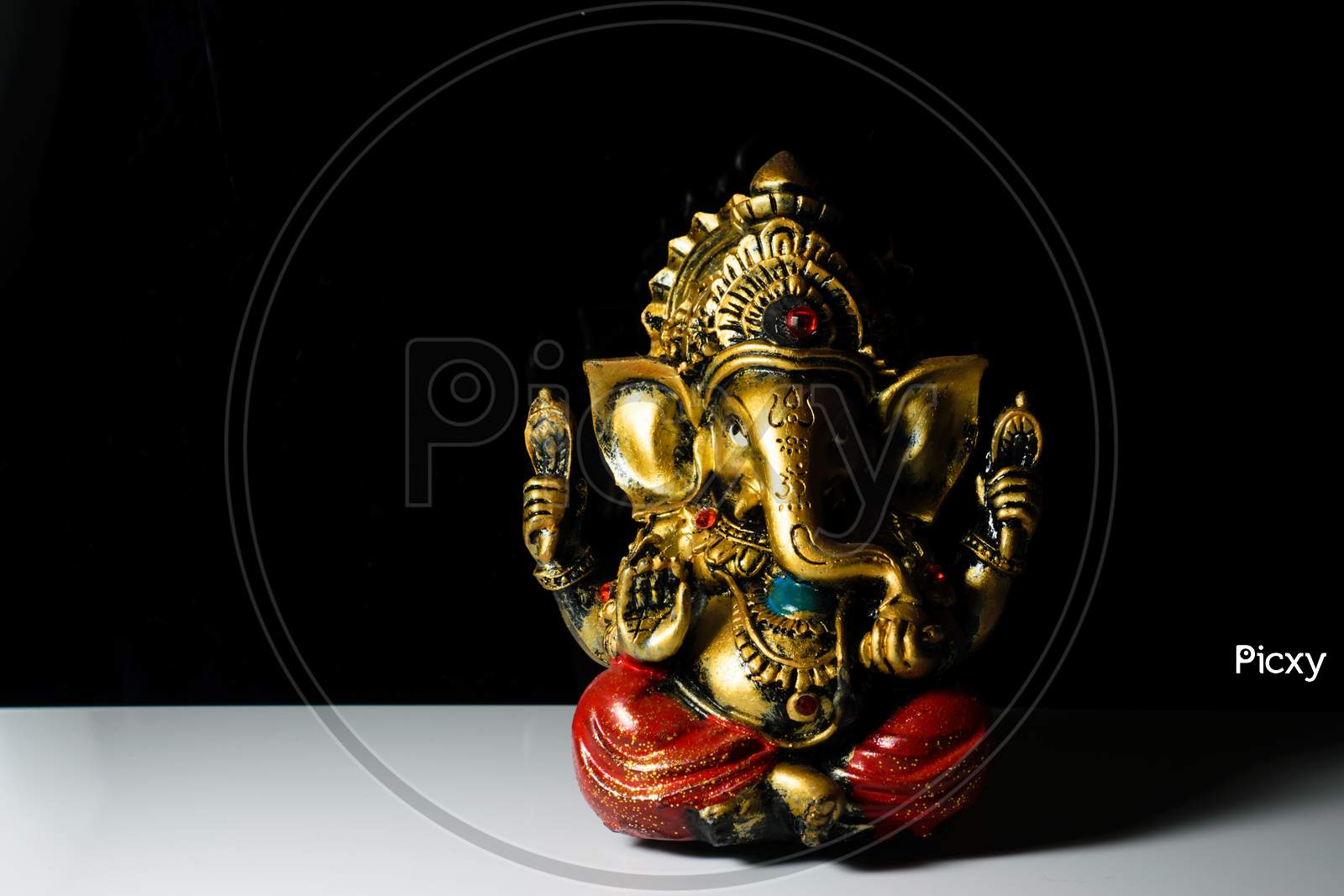An Isolated Sculpture Of The Indian God Ganesha Placed On A Reflective White Table In A Dark Background