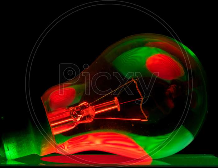 Bangladeshi Flag'S Reflection On A Tungsten Light Bulb,On A Green Surface With Dark Background In A Creative Way.Bangladeshi Flag'S Reflection On A Tungsten Light Bulb,On A Green Surface