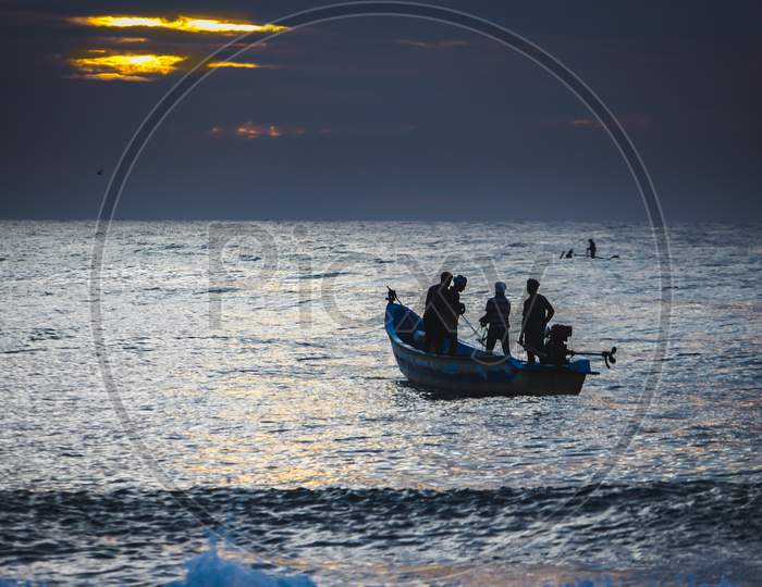 Kovalam, Tamildadu, India - June 13Th 2020: Local Fishermen Start Their Work At Early Morning In Coast And Pulling Their Fishing Boat Out Of The Sea Near Chennai. Firsherman On Boat At Sunsrise,