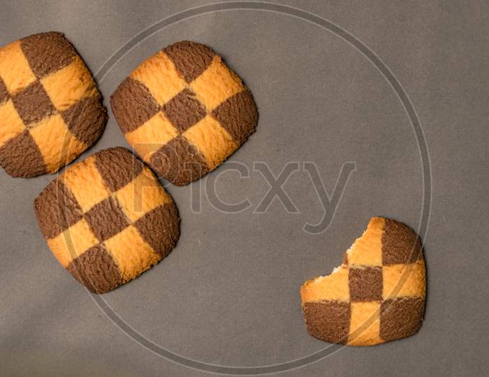 Four Checker Board Cookies In Plain Black Background