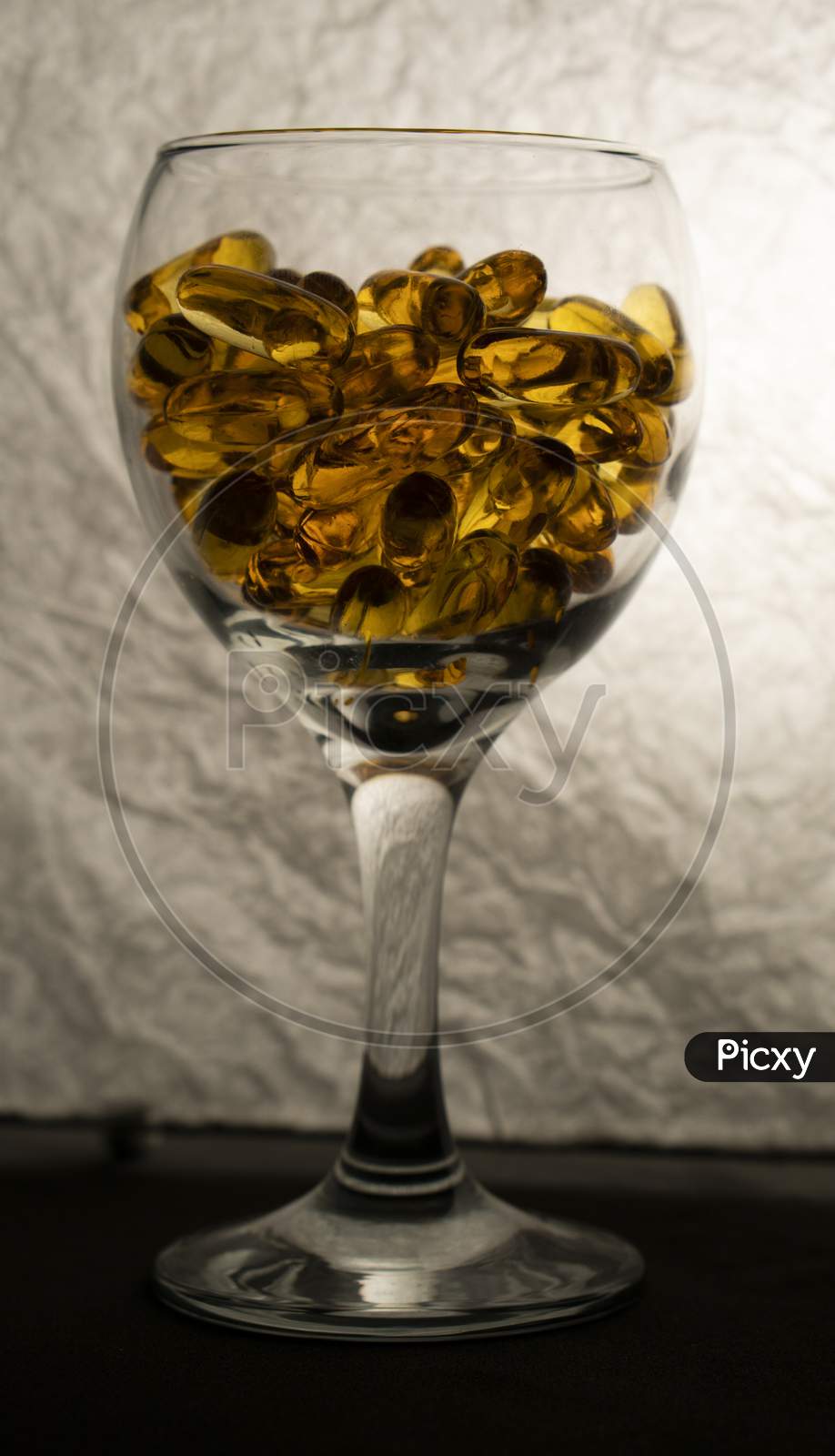 Omega-3 capsules in a glass on a white background.