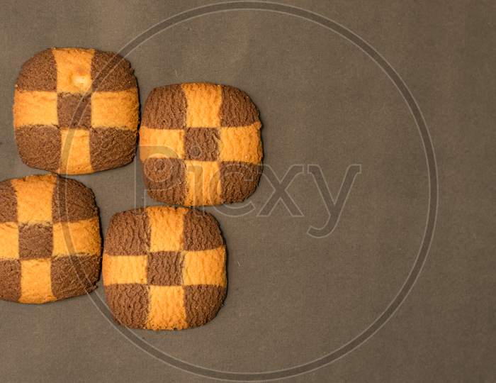 Four Checker Board Cookies In Plain Black Background