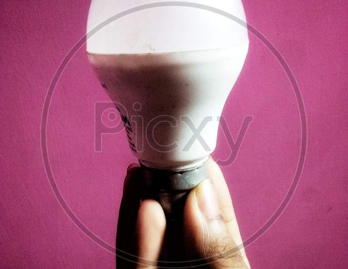 Hand holding Bright bulb on pink background