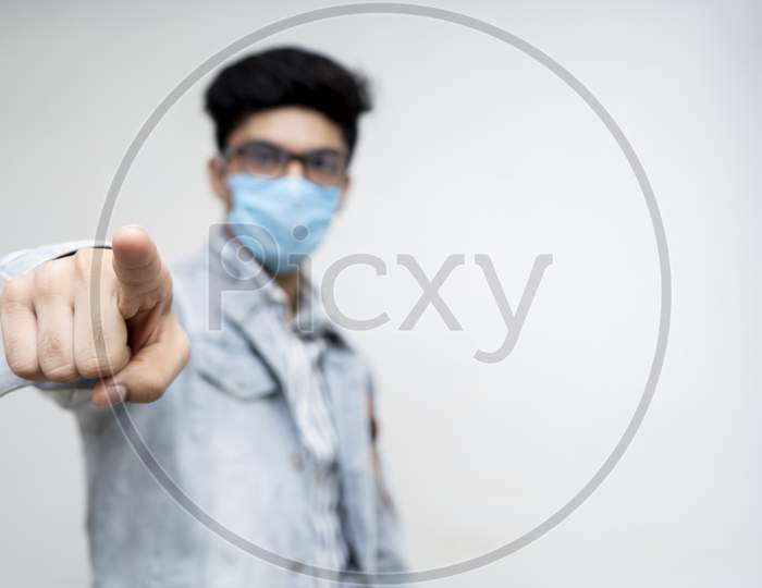 A Young Boy Wearing A Protection Mask On His Face Pointing A Finger Towards The Camera, Selective Focus.