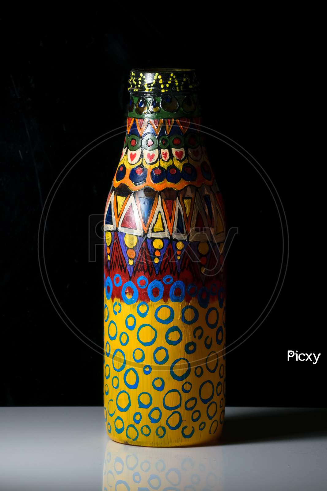 An Artwork Over An Empty Bottle Put On A White Surface In A Dark Background