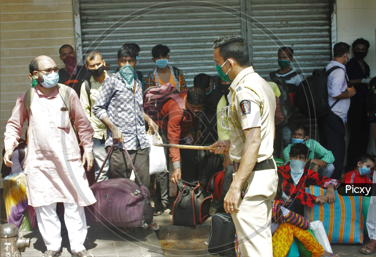 A policeman instructs the migrants to form a proper queue and not gather in huge numbers, who are waiting to go to CSMT,  that will take them to their home state during an extended lockdown to slow the spreading of the coronavirus disease (COVID-19), in Mumbai, India, May 30, 2020.