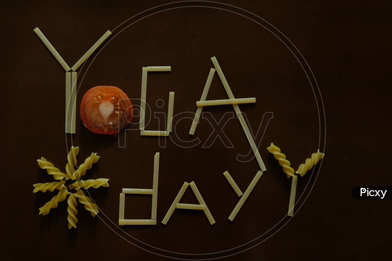 Yoga day text with spaghetti and tomato on a dark background