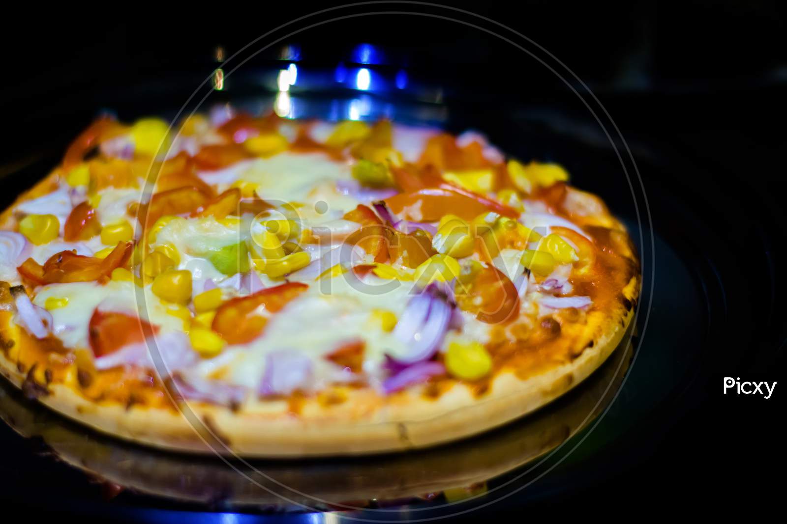 Cutting cheese pizza with Pizza cutter, with tomato, onion, corn toppings, with selective focus in lockdown.