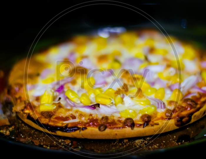 Fresh Homemade cheese pizza, with tomato, onion, corn toppings, with selective focus in lockdown.