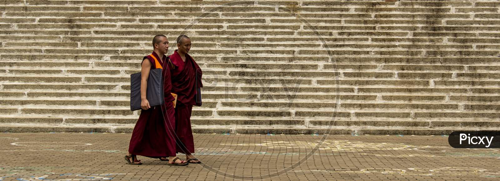Two Tibetan Monks walking in a Buddhist Monastery in Bylukoppa /India.