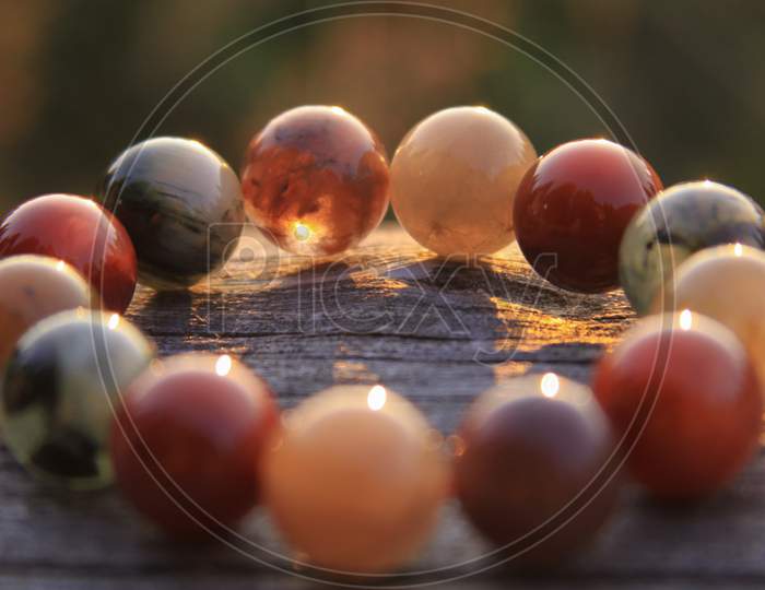 Round Gemstone Beads In Circle On Wood Shining In Sunlight