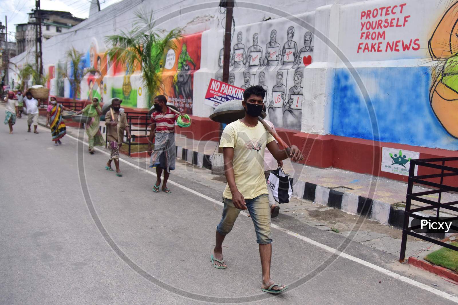 Labourers walk Past A Mural  With A Message To Take Precautions Against Coronavirus In Guwahati , India On June 14, 2020.