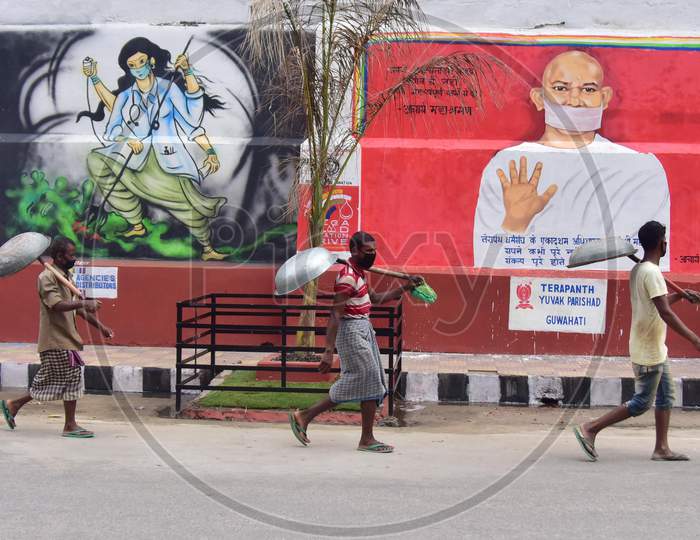 Labourers walk Past A Mural  With A Message To Take Precautions Against Coronavirus In Guwahati , India On June 14, 2020.