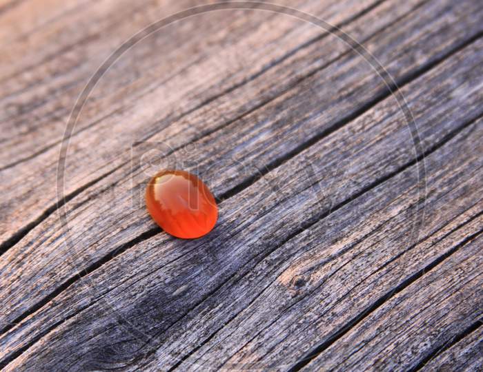 Isolated Red Chalcedony Agate Gemstone On Wooden Background