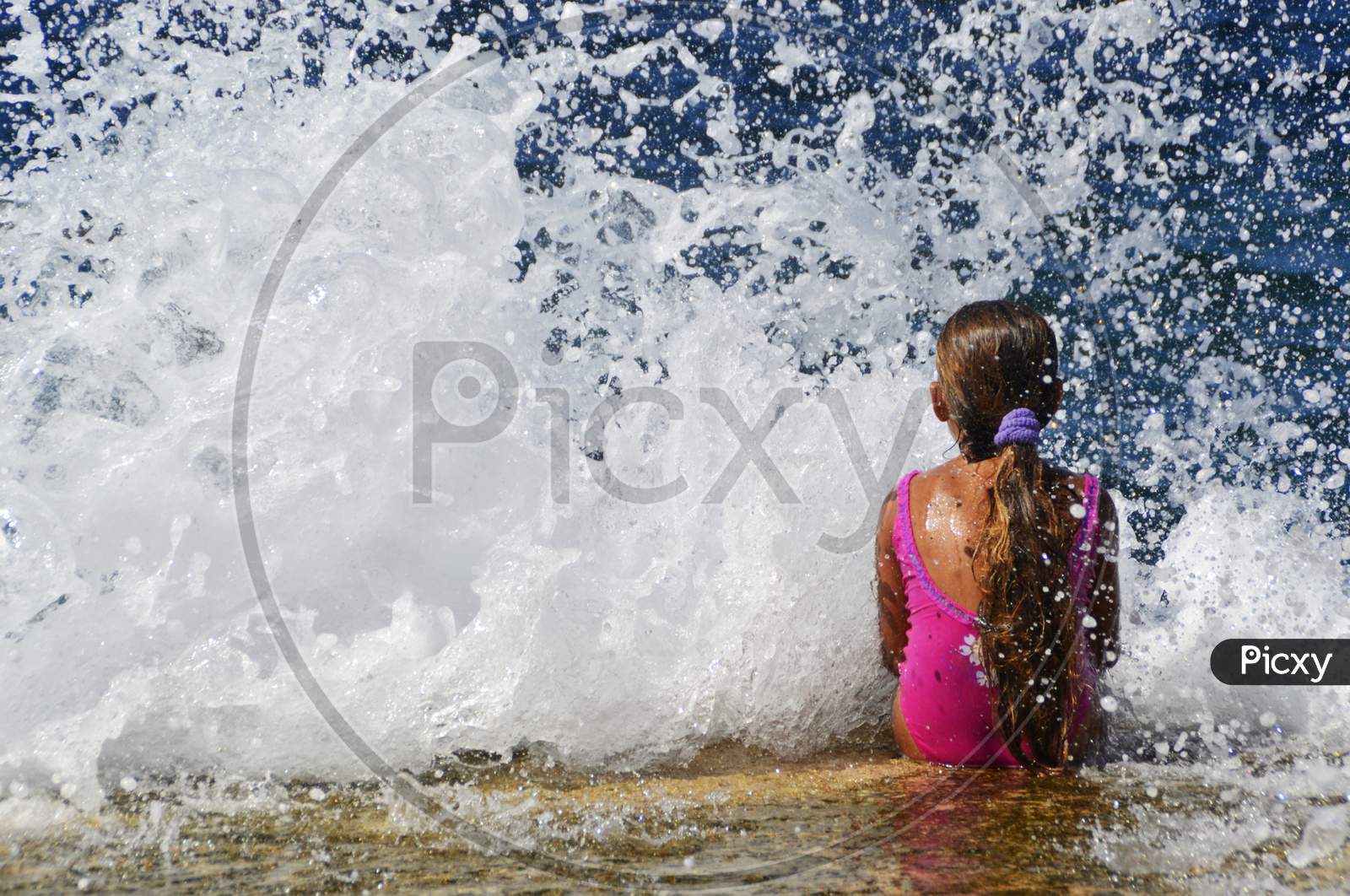 Little girl stays in front of waves