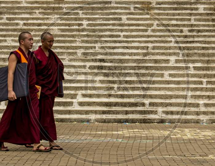 Two Tibetan Monks walking in a Buddhist Monastery in Bylukoppa /India.