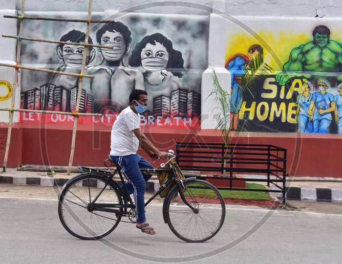 A Man Rides A Bicycle Past A Wall Graffiti Which Was Made To Honour Medical Workers Who Fight Against The Coronavirus In Guwahati, India On June 14, 2020.