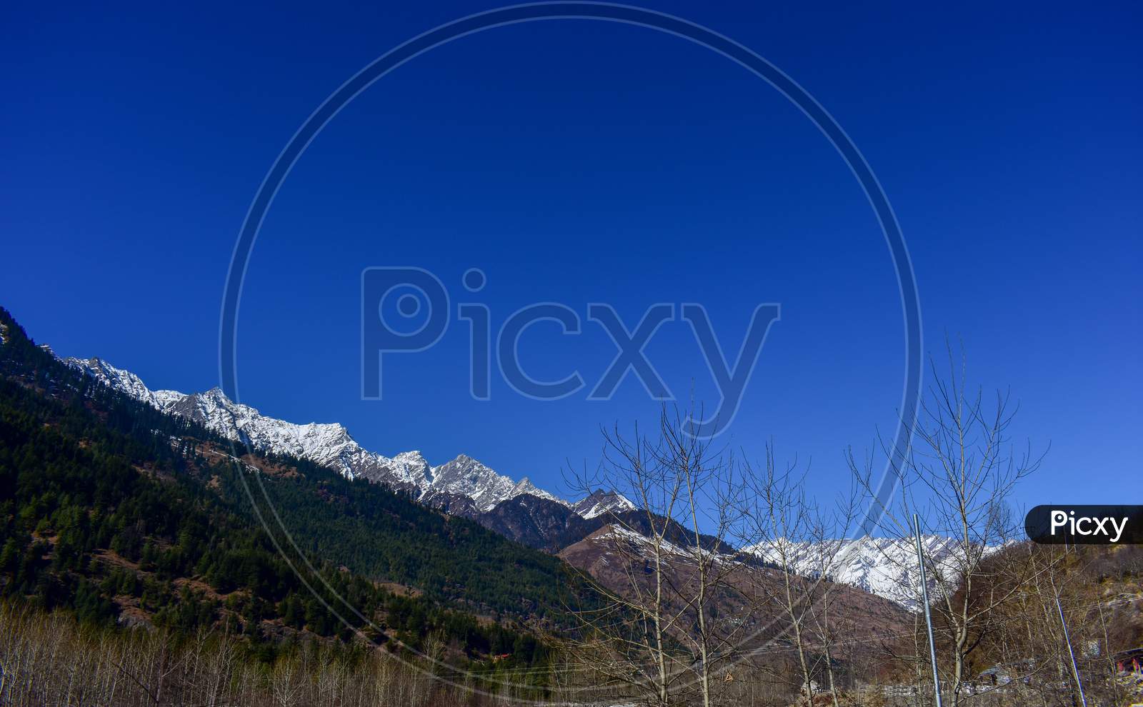 View of Himachal Pradesh, India snow covered mountains over beautiful blue sky.