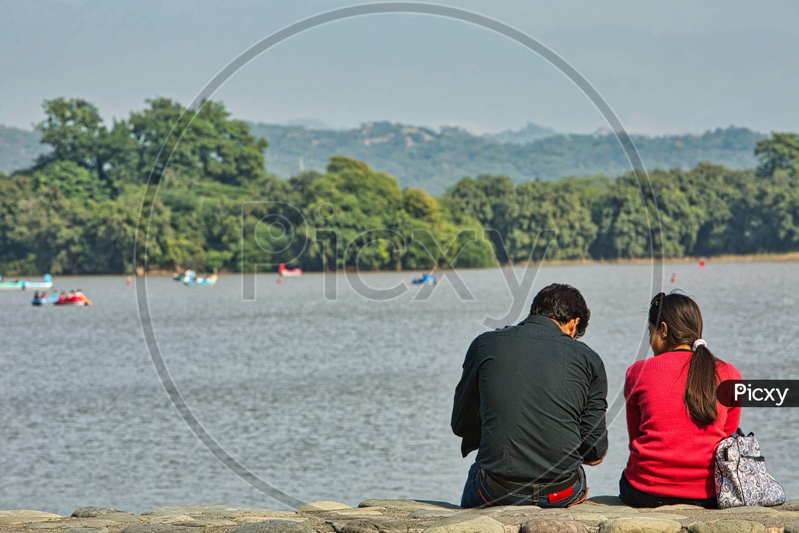 Chandigarh, India - November 26Th, 2012: A Couple Chatting On The Bank Of Sukhna Lake In Chandigarh, India. It Is A Man Made Reservoir At The Foothills Of The Himalayas