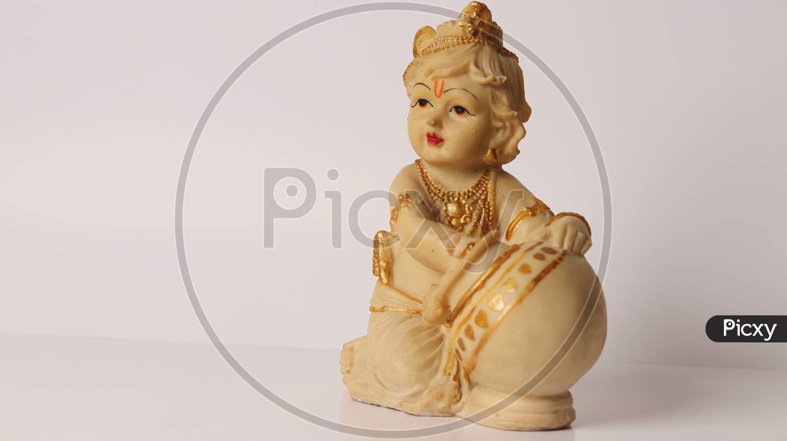 Close up of Lord Krishna with butter pot idol