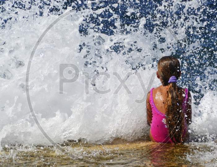 Little girl stays in front of waves