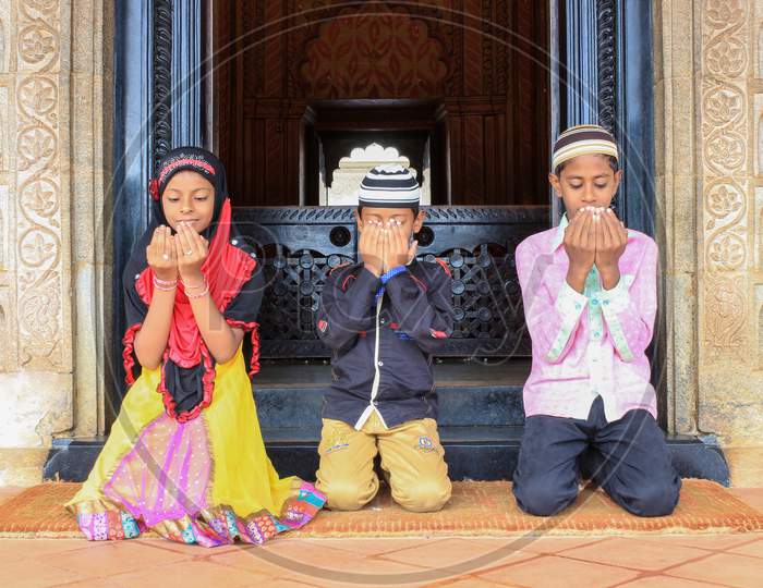 Three Muslim kids offering prayers in Tipu's Tomb in Srirangapatna/India.