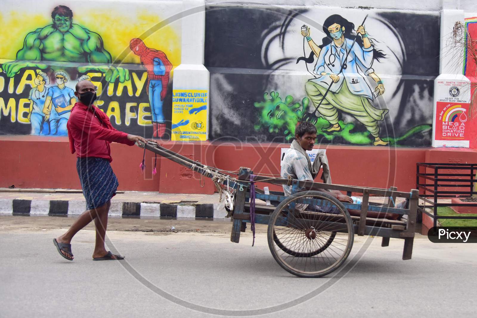 A Labourer Pushes A Handcart Past A Wall Graffiti Which Was Made To Honour Medical Workers Who Fight Against The Coronavirus In Guwahati, India On June 14, 2020.