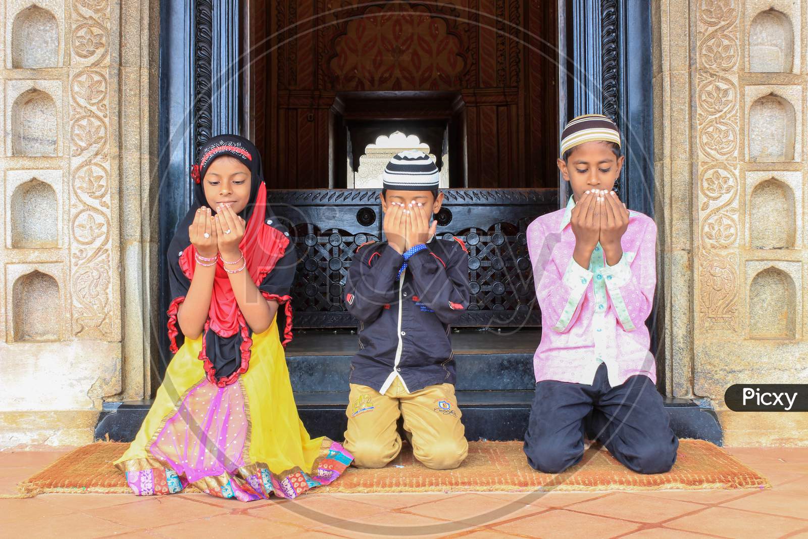Three Muslim kids offering prayers in Tipu's Tomb in Srirangapatna/India.