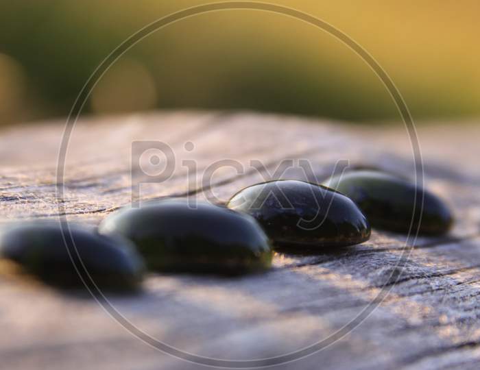 Four Black Jade Translucent Gemstones On Wood