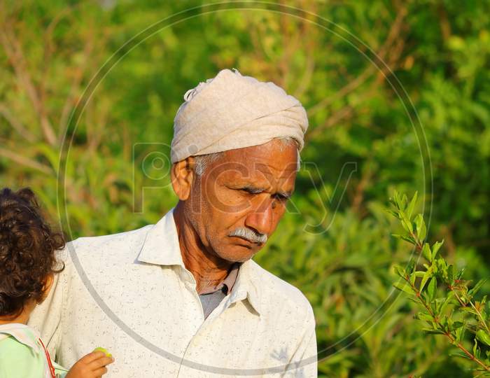 A Grandfather Stands With A Grandson In His Hands In The Garden