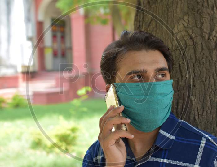 indian man calling on phone wih mask on face