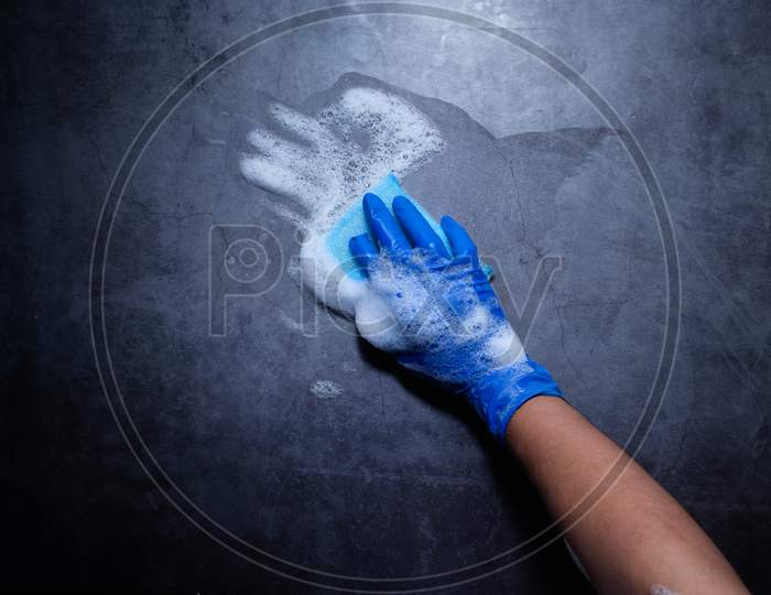 Man In Protective Rubber Gloves Holding A Sponge And Clean Black Surface