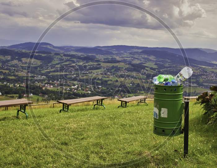 A Landscape Of Mountains, Bench, Greenfield And A Garbage Or Trash Bin Located In Small Town In South Poland, Europe