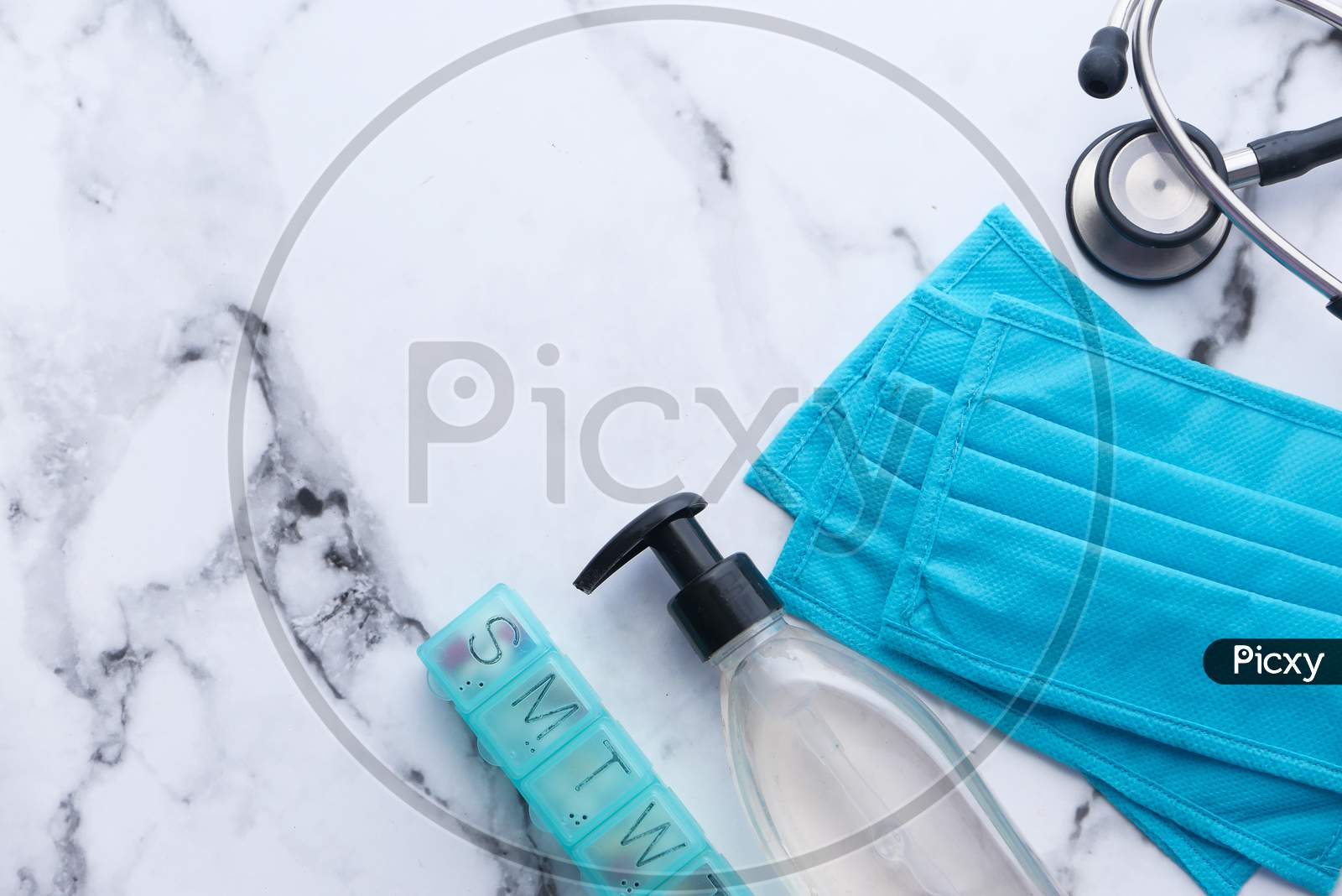 Surgical Masks, Sanitizer, Stethoscope And Pill Box On White Background