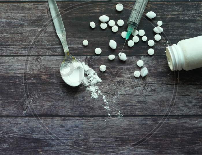 Heroine, Syringe And Pills On Wooden Background.