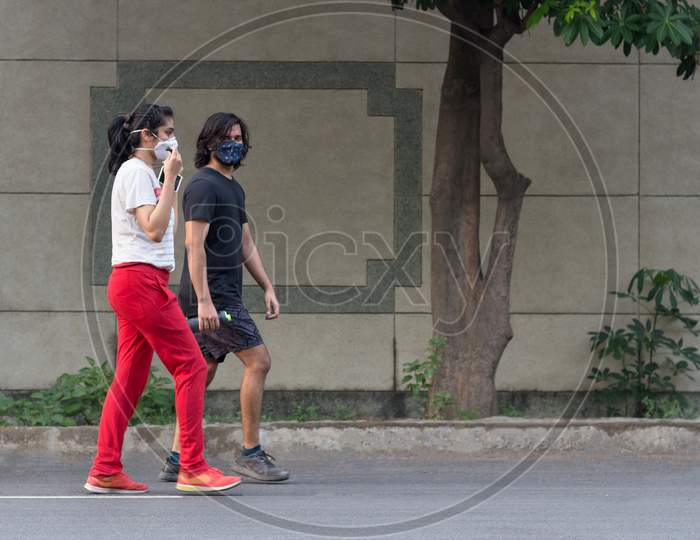 Young Couple Wearing Masks While Walking.