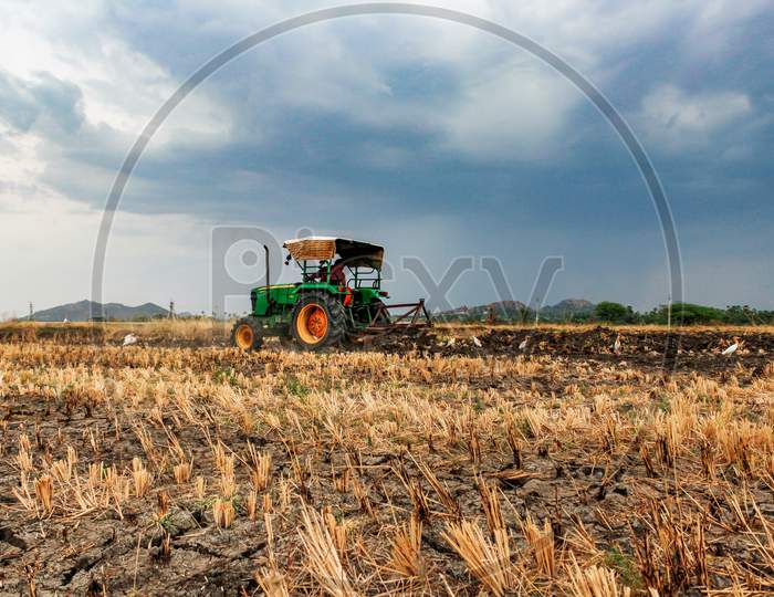 Farmer ploughing the field by tractor in Kharif season