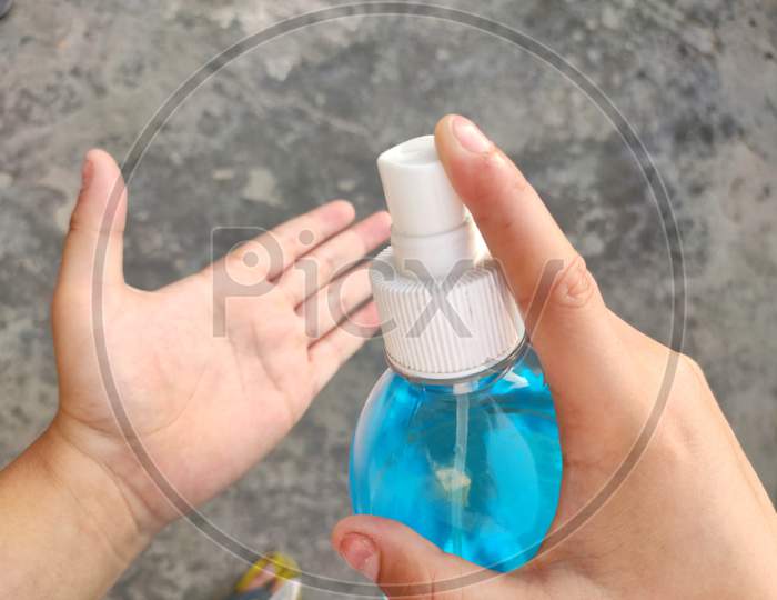 Closeup of a boy sanitizing his hand.