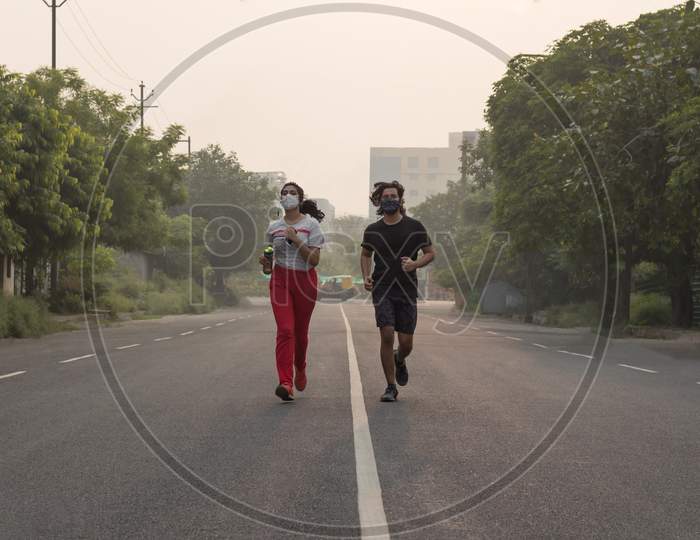 Young Couple Wearing Masks While Running In The Morning.