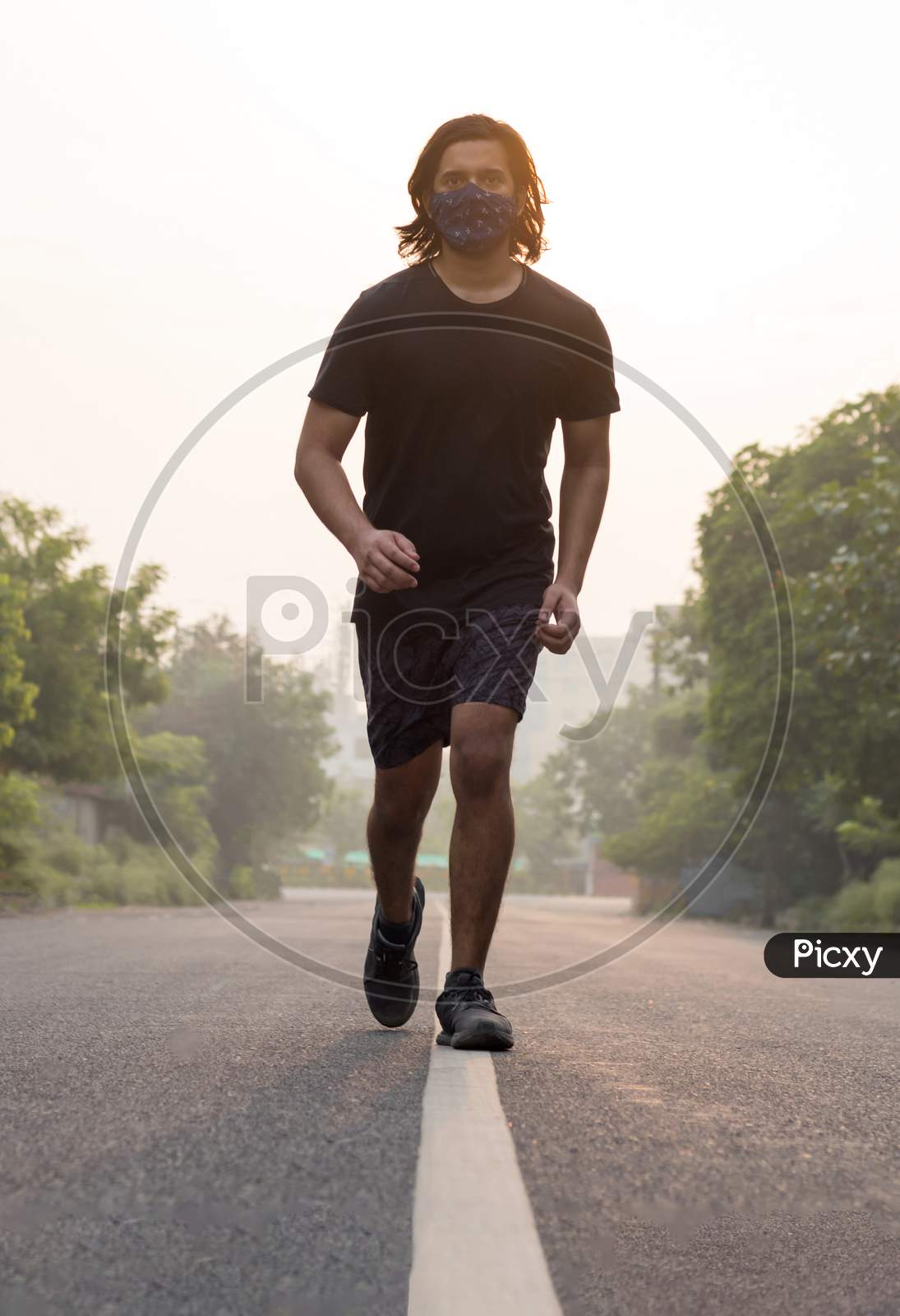 A Man Wearing Mask While Running During Sunrise.