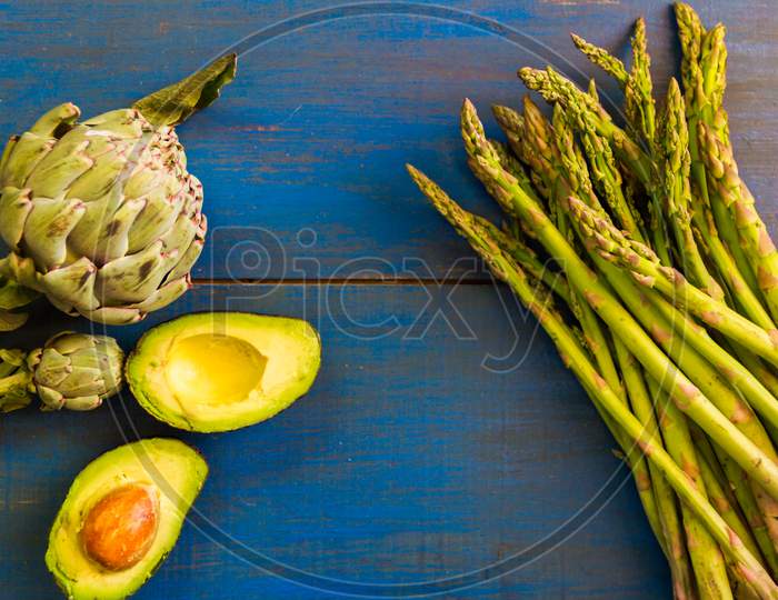 Artichokes, Asparagus And Avocados On Blue Wooden Rustic Background