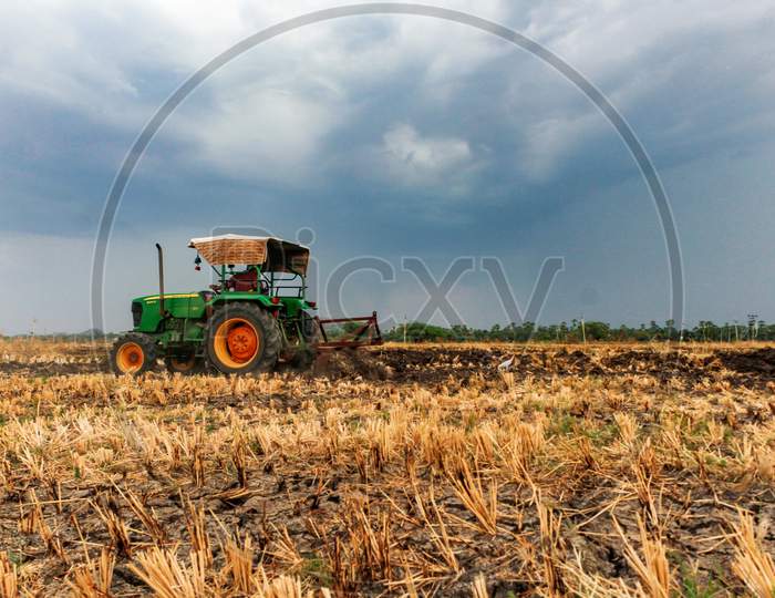 Farmer ploughing the field by tractor in Kharif season