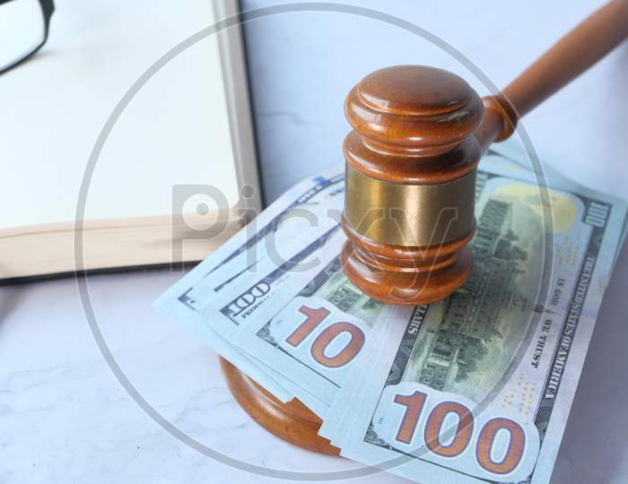 Close Up Of Gavel, Cash And Open Book On White Desk