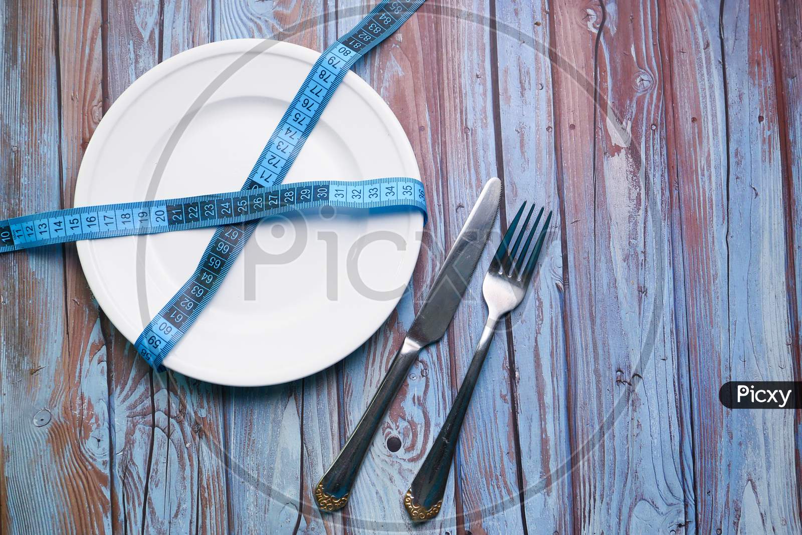 Clean Plate With Measurement Tape And Cutlery On Wooden Background