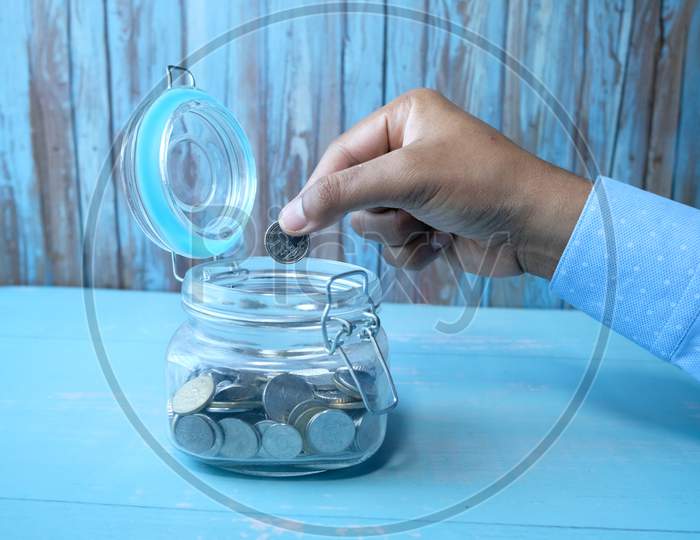 Close Up Of Man Saving Coins In A Jar