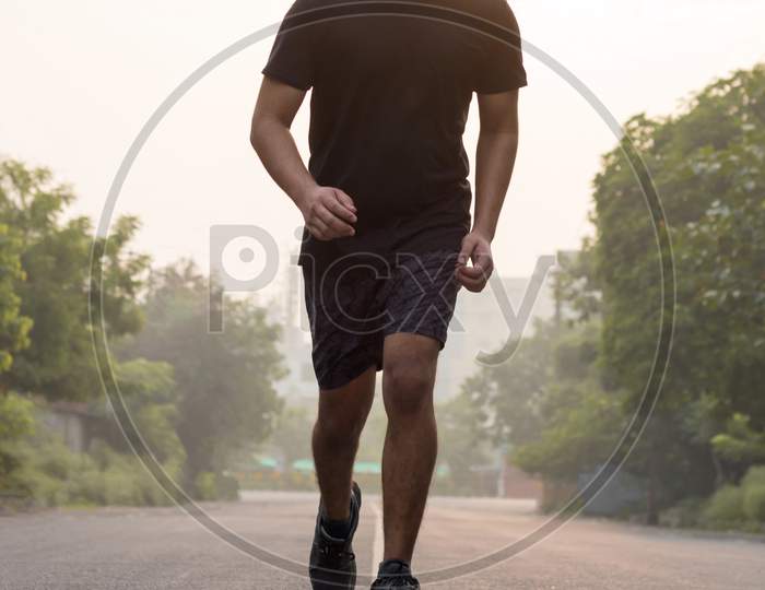 A Man Wearing Mask While Running During Sunrise.