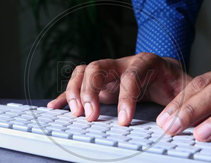 Young Man Typing On Keyboard At Office Desk
