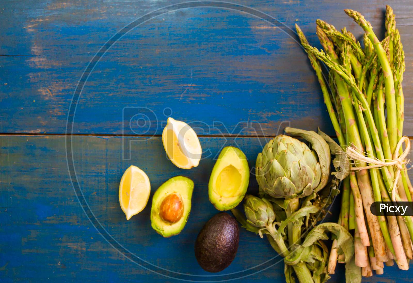 Artichoke Avocados And Asparagus On Blue Rustic Background