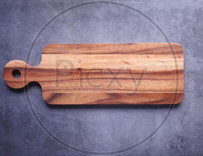 Top View Of Wooden Chopping Board On Gray Background .